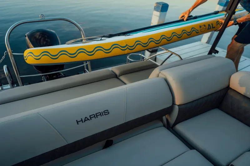 Slide: The Image of A 2027 Harris 210SL with gray seating and a yellow paddleboard on a dock. - 15