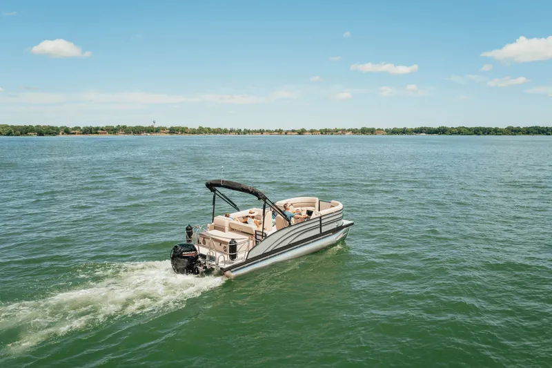 Slide: The Image of A Harris 210SL pontoon boat cruising on a calm lake under a blue sky. - 4