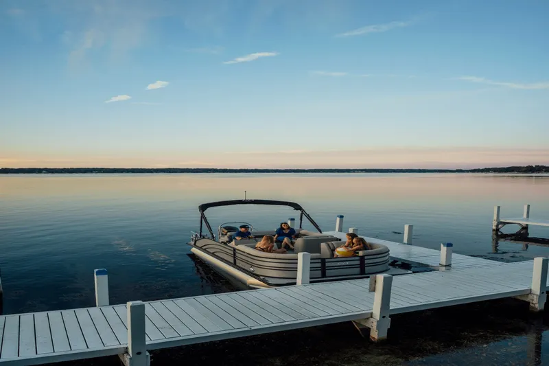 Slide: The Image of Harris 210SL pontoon boat at a dock, surrounded by calm water and a clear sky. - 19