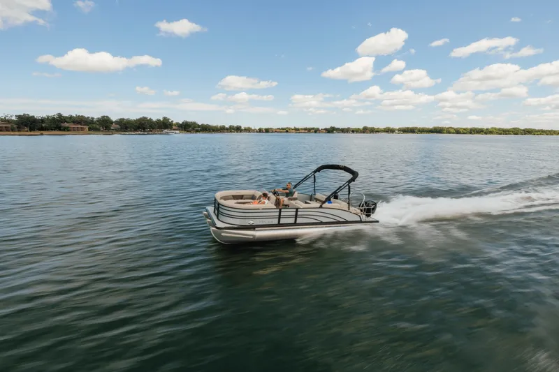 Slide: The Image of A Harris 210SL pontoon boat speeds across a calm lake under a blue sky. - 1
