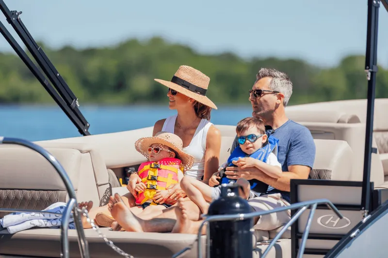 Slide: The Image of Family relaxing on a Harris 210SL pontoon boat, surrounded by water and trees. - 30