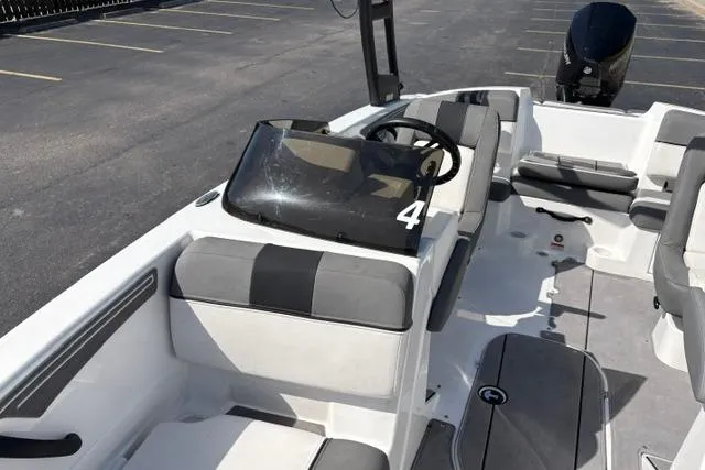 Slide: The Image of 2024 Tahoe T21 boat interior with gray seating and steering wheel, parked in a lot. - 8