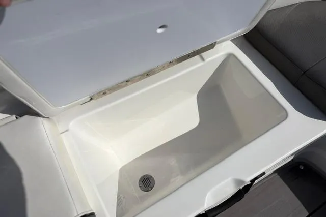 Slide: The Image of Open storage compartment in 2024 Tahoe T21 boat, featuring a drain plug. - 38