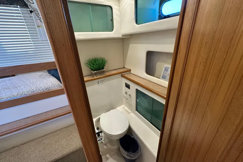 Slide: The Image of Bayliner 4087 Aft Cabin Motoryacht 2000 bathroom with toilet, storage, and porthole window. - 24