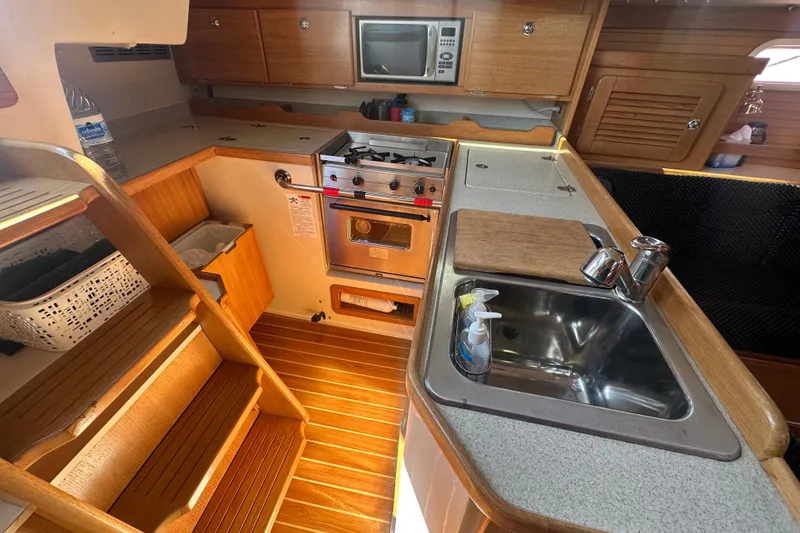 Slide: The Image of 2005 Catalina 36 MkII yacht kitchen with wooden cabinetry, stove, sink, and microwave. - 8