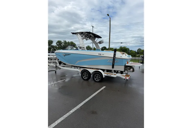 Slide: The Image of 2023 Tigé Z1 boat on trailer, light blue exterior, parked on wet pavement under cloudy sky. - 3