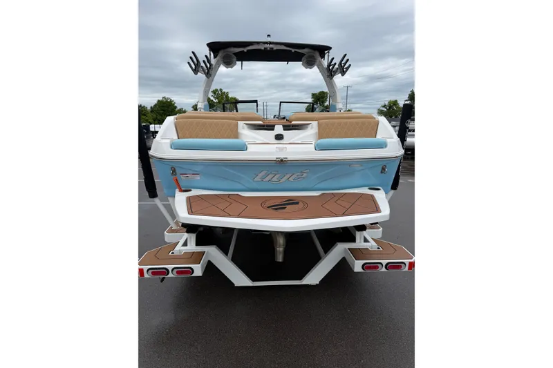 Slide: The Image of 2023 Tigé Z1 boat rear view with blue and tan seating, parked outdoors. - 2