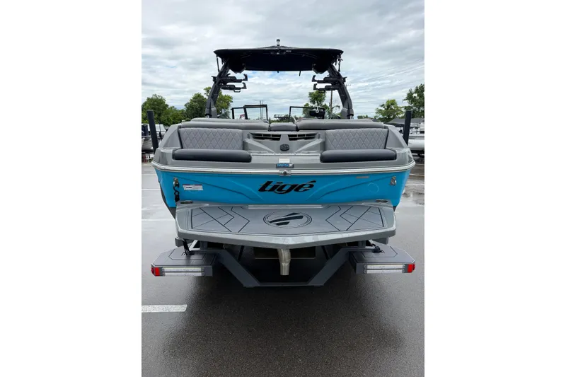 Slide: The Image of 2023 Tigé Z1 boat, rear view, blue exterior, parked on wet pavement. - 7