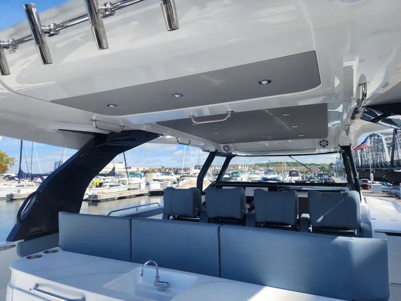Slide: The Image of The image shows the cockpit of a 2027 Cruisers Yachts 45VTR. It features modern seating with blue upholstery and a small sink. A marina and boats are visible in the background. - 29