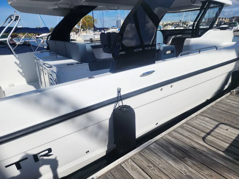 Slide: The Image of A modern yacht with a white hull docked at a wooden pier. Other boats are visible in the background. - 8