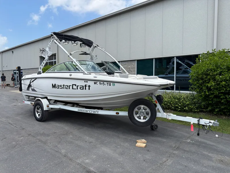 Slide: The Image of A white 2011 MasterCraft X2 boat on a trailer in front of a building. - 2