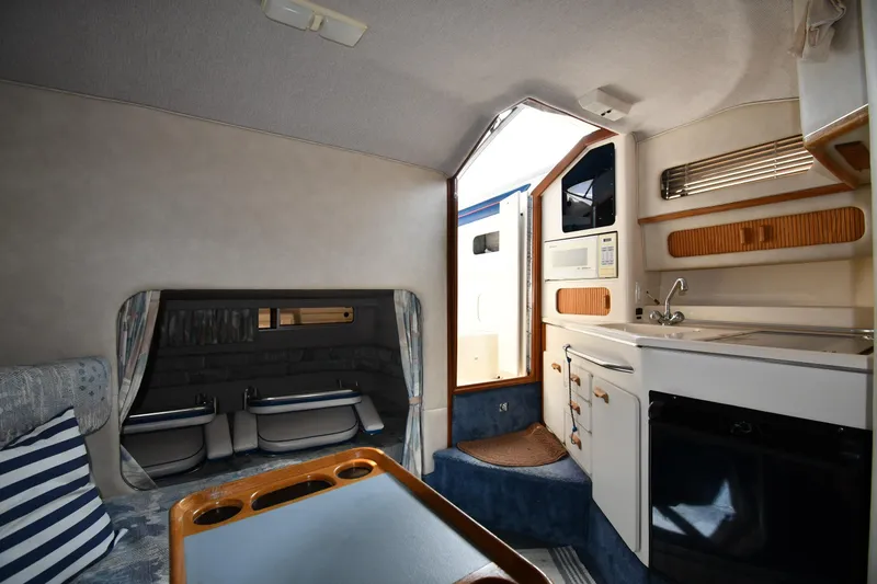 Slide: The Image of Interior of a 1993 Sea Ray 300 Sundancer boat, featuring a kitchenette and seating area. - 26