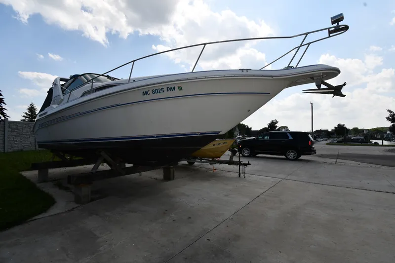 Slide: The Image of 1993 Sea Ray 300 Sundancer boat on trailer, parked outdoors under a partly cloudy sky. - 4