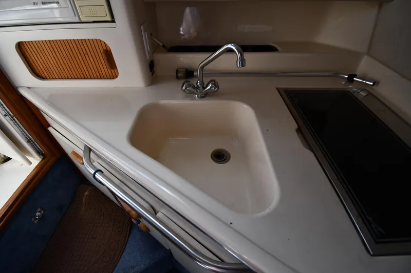 Slide: The Image of 1993 Sea Ray 300 Sundancer kitchen area with sink and stove. - 31