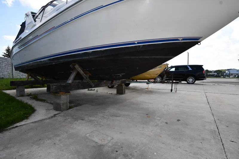 Slide: The Image of 1993 Sea Ray 300 Sundancer boat on blocks in a parking area. - 3
