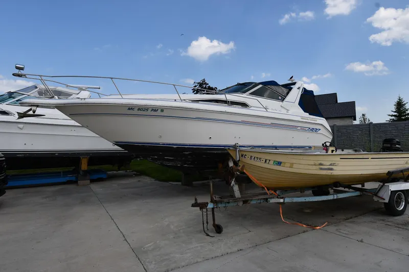 The Image of 1993 Sea Ray 300 Sundancer boat on trailer, parked outdoors under a clear blue sky. - 1