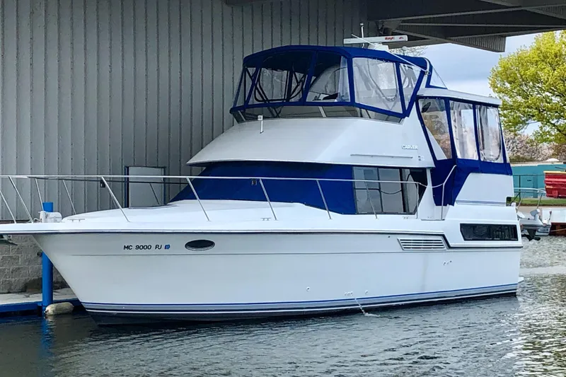 The Image of 1992 Carver 33 Aft Cabin Motor Yacht docked, featuring blue canopy and sleek design. - 0