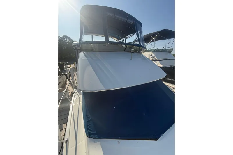Slide: The Image of 1992 Carver 33 Aft Cabin Motor Yacht with blue canopy, docked under clear sky. - 8