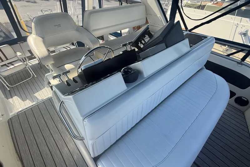 Slide: The Image of 1992 Carver 33 Aft Cabin Motor Yacht helm with white seating and steering wheel. - 24