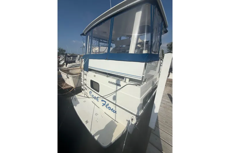 Slide: The Image of 1992 Carver 33 Aft Cabin Motor Yacht docked, featuring blue canopy and white hull. - 2