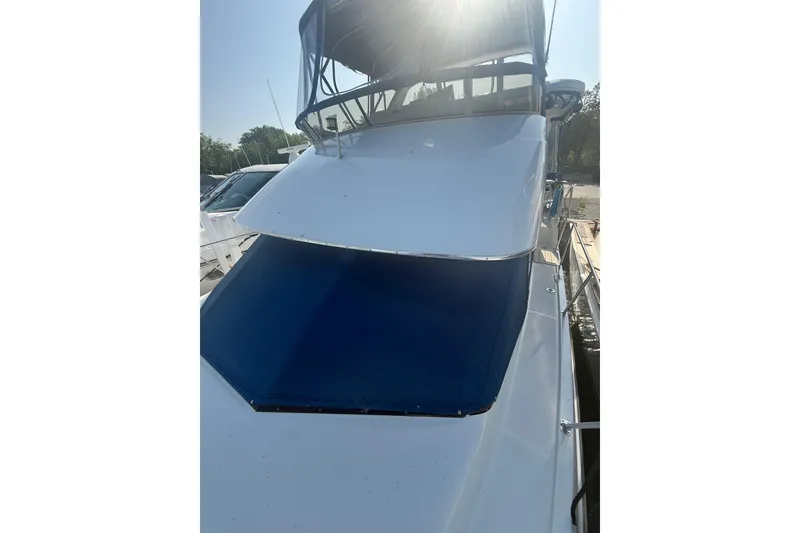 Slide: The Image of 1992 Carver 33 Aft Cabin Motor Yacht with blue canopy, docked under sunlight. - 7