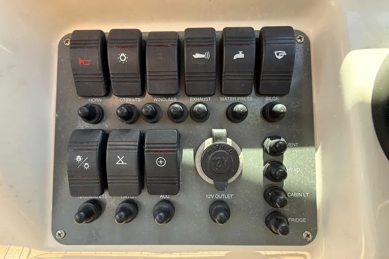 Slide: The Image of Control panel of a 2005 Chris-Craft Launch 28 boat with various switches and 12V outlet. - 14