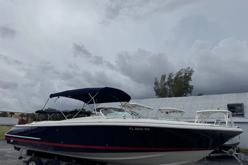 Slide: The Image of 2005 Chris-Craft Launch 28 boat with canopy, parked outdoors under cloudy skies. - 3