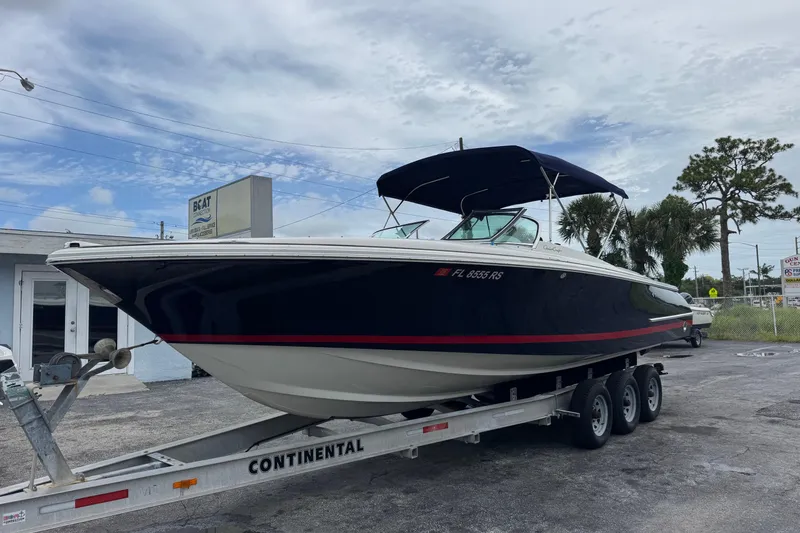 The Image of 2005 Chris-Craft Launch 28 boat on trailer, parked outdoors under cloudy sky. - 0