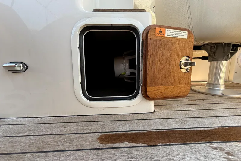 Slide: The Image of Storage compartment on a 2005 Chris-Craft Launch 28 boat with wooden door and warning label. - 32