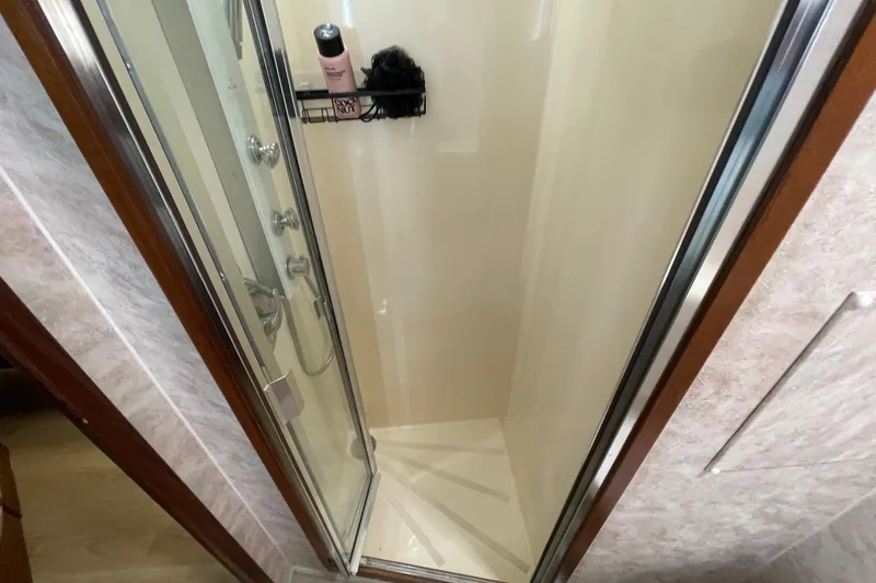 Slide: The Image of Shower area inside a 1990 Hatteras 45 Convertible yacht, featuring glass door and toiletries. - 63