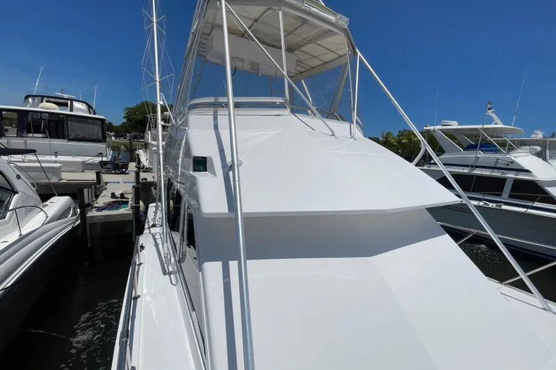 Slide: The Image of 1990 Hatteras 45 Convertible yacht docked at marina under clear blue sky. - 49
