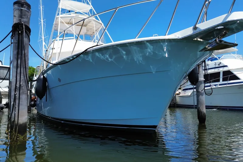 Slide: The Image of 1990 Hatteras 45 Convertible yacht docked in marina, clear blue sky background. - 14