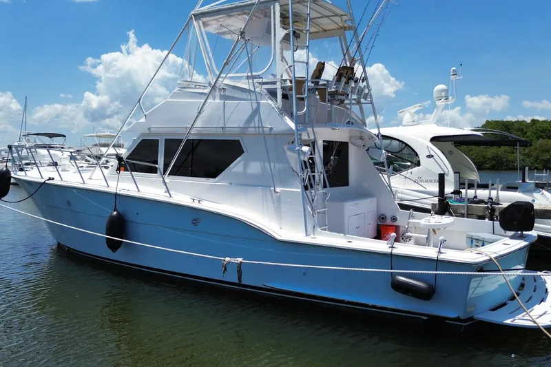 Slide: The Image of 1990 Hatteras 45 Convertible yacht docked in sunny marina, showcasing sleek design and fishing tower. - 20
