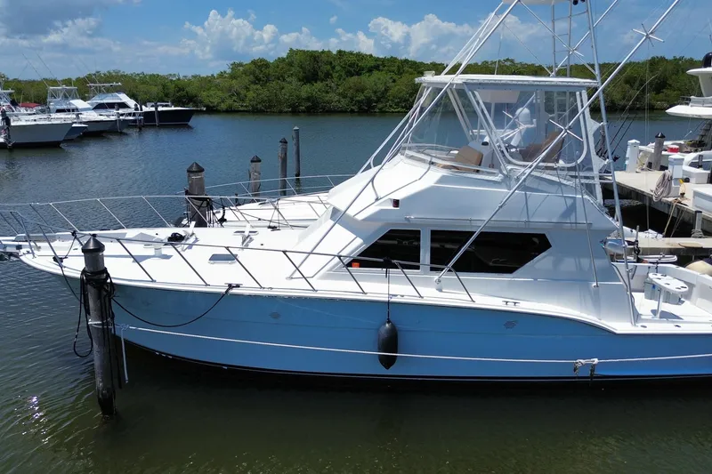 Slide: The Image of 1990 Hatteras 45 Convertible yacht docked in a serene marina setting. - 7