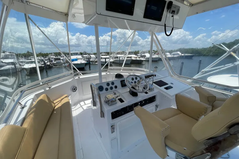 Slide: The Image of Helm of 1990 Hatteras 45 Convertible yacht with marina view and beige seating. - 34
