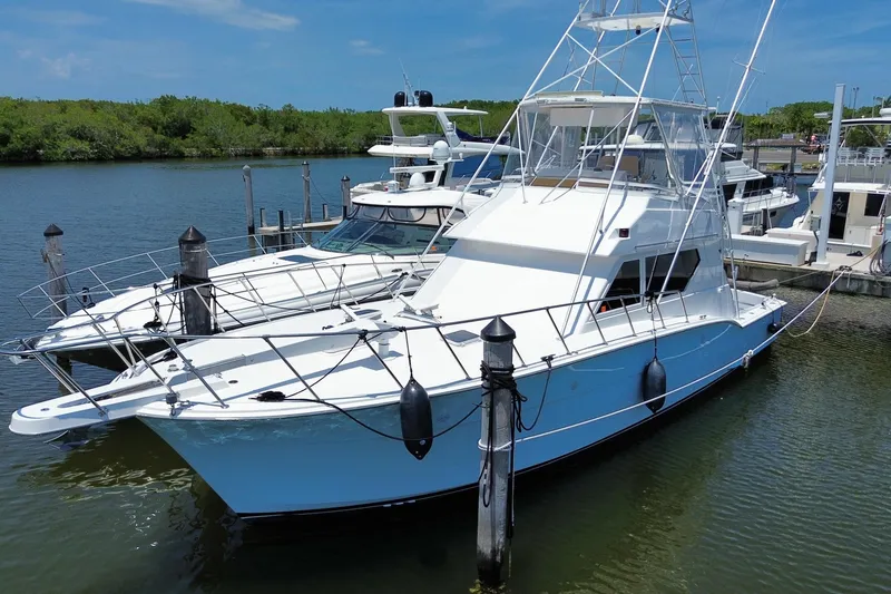 Slide: The Image of 1990 Hatteras 45 Convertible yacht docked at marina under clear blue sky. - 12