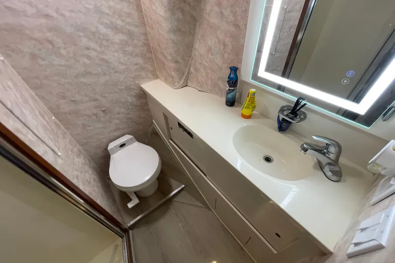 Slide: The Image of Bathroom interior of 1990 Hatteras 45 Convertible yacht, featuring sink, toilet, and illuminated mirror. - 64