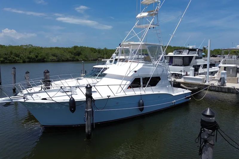 Slide: The Image of 1990 Hatteras 45 Convertible yacht docked at marina under clear blue sky. - 2