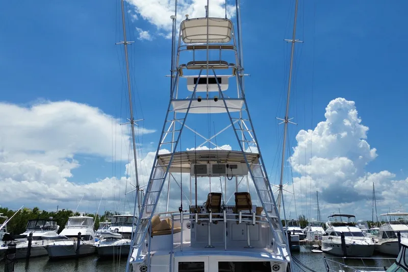 Slide: The Image of 1990 Hatteras 45 Convertible yacht with tower, docked under a bright blue sky. - 23