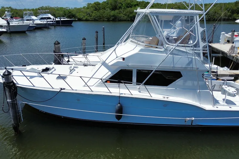 Slide: The Image of 1990 Hatteras 45 Convertible yacht docked in a serene marina setting. - 11