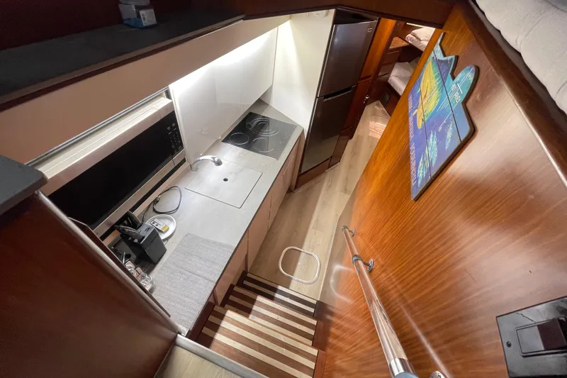 Slide: The Image of Interior of 1990 Hatteras 45 Convertible yacht, featuring a compact kitchen and wooden finishes. - 55