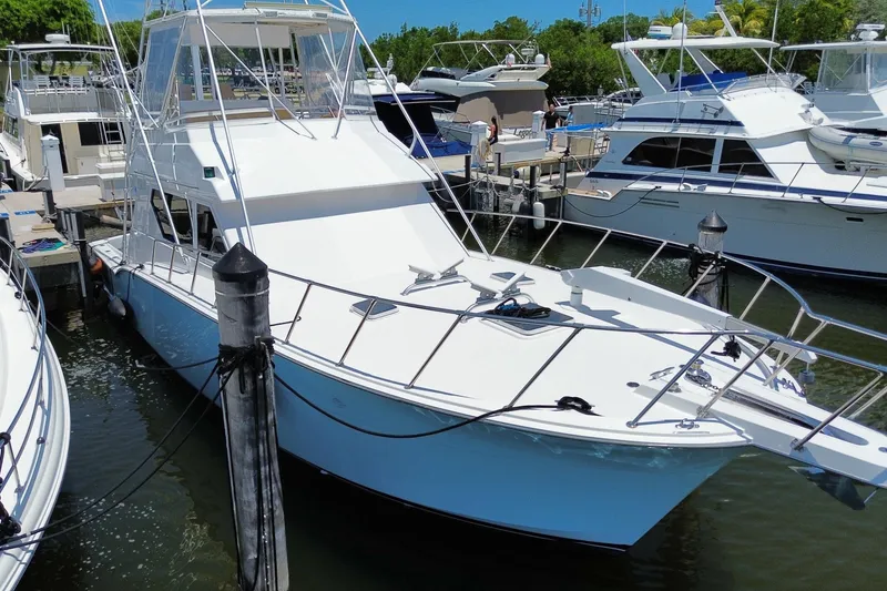 Slide: The Image of 1990 Hatteras 45 Convertible yacht docked at marina, surrounded by other boats. - 3