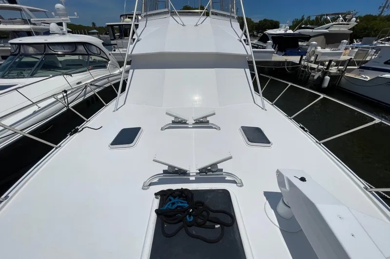 Slide: The Image of 1990 Hatteras 45 Convertible yacht deck, docked among other boats, featuring sleek white design. - 47
