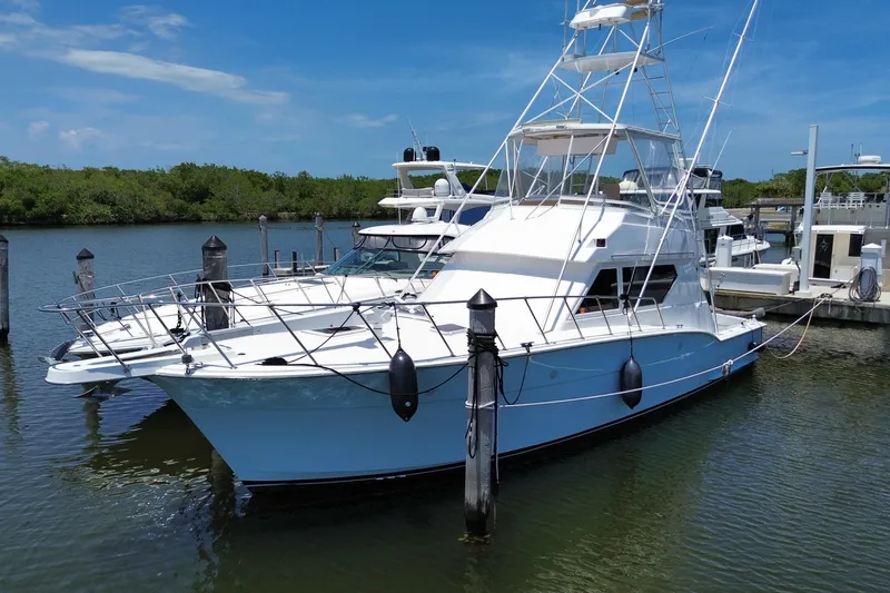 Slide: The Image of 1990 Hatteras 45 Convertible yacht docked in a marina under clear blue skies. - 19