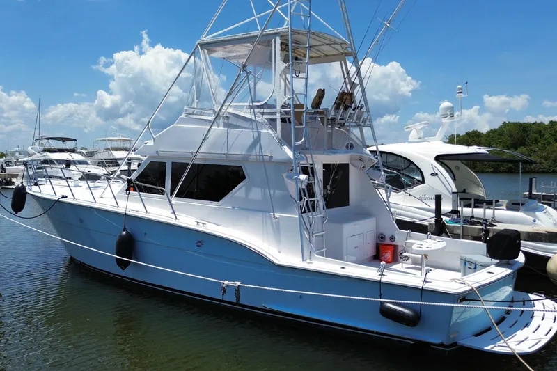Slide: The Image of 1990 Hatteras 45 Convertible yacht docked in a marina under a clear blue sky. - 21