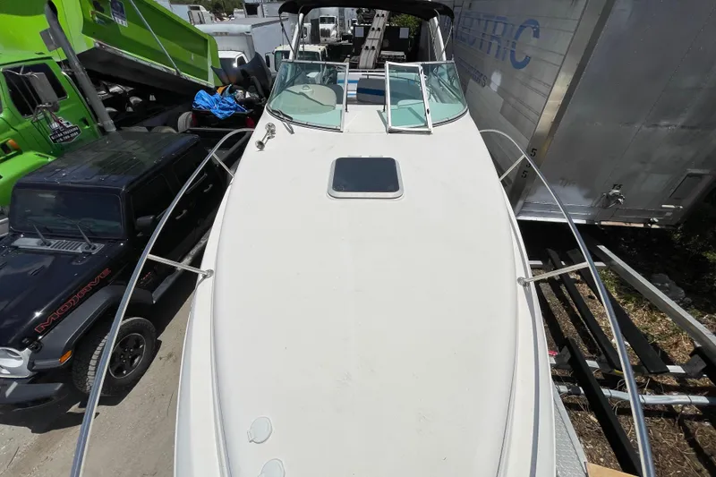 Slide: The Image of 2000 Rinker 280 Express Cruiser boat docked, surrounded by vehicles and trailers. - 26