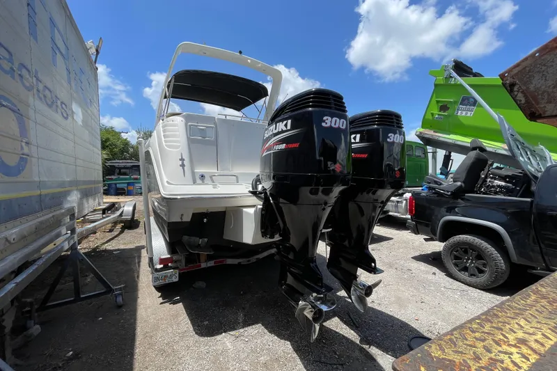Slide: The Image of 2000 Rinker 280 Express Cruiser with twin Suzuki 300 outboard motors, parked outdoors. - 50