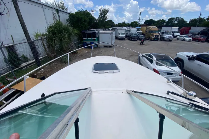 Slide: The Image of 2000 Rinker 280 Express Cruiser docked in a busy parking lot under a clear sky. - 27