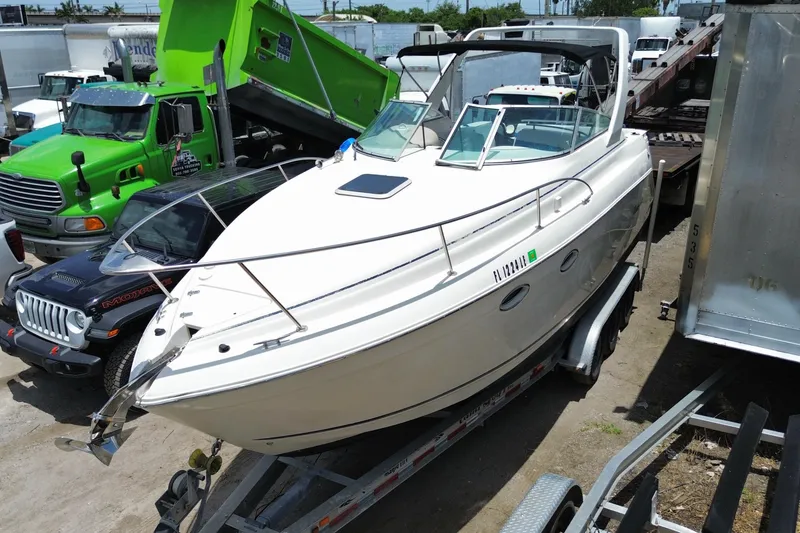 Slide: The Image of 2000 Rinker 280 Express Cruiser on trailer, surrounded by vehicles in a parking area. - 11