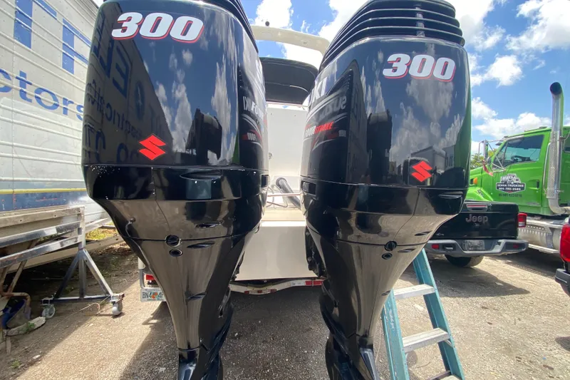 Slide: The Image of Twin Suzuki 300 outboard engines on a 2000 Rinker 280 Express Cruiser, parked outdoors. - 52